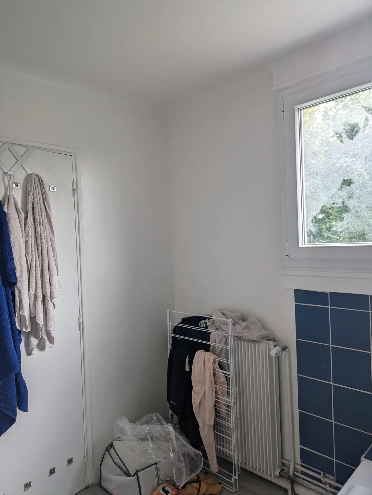 Avant rénovation : mur de la salle de bains avec fenêtre et radiateur